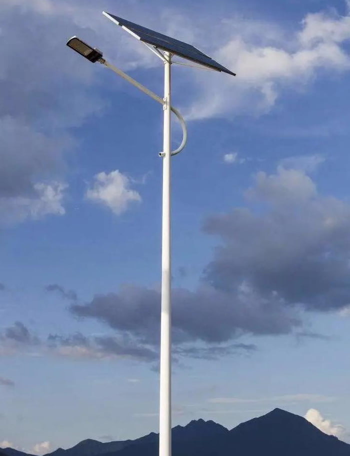 A classic single lamppost with a light on top against a blue sky